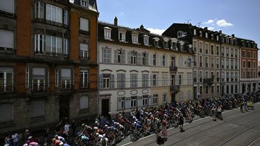 The pack of riders (peloton) cycles in the streets of Mulhouse at the start of the 14th stage of the 113th edition of the Tour de France cycling race, 155,3 km between Mulhouse and Le Markstein in the Vosges mountains, on July 18, 2026. 
Loic VENANCE / AFP