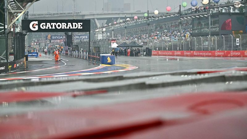 A track marshal looks on as he sweeps rain water off the track before the start of the sprint race ahead of the Formula One Singapore Grand Prix at the Marina Bay Street Circuit in Singapore on October 10, 2026. 
ANTHONY WALLACE / AFP