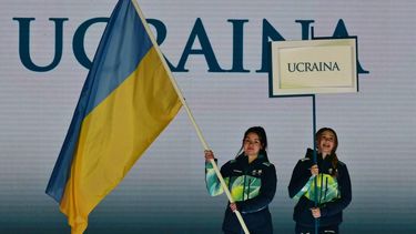 Volunteers hold a flag of Ukraine and a placard during the delegation part of the Milano Cortina 2026 Winter Paralympic Games opening ceremony at Arena di Verona in Verona on March 6, 2026. 
Stefano RELLANDINI / AFP
