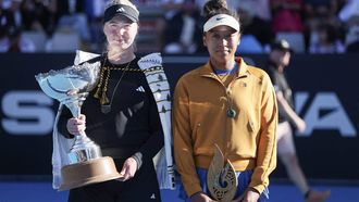 Clara Tauson of Denmark (L) celebrates with the trophy after her win over Naomi Osaka of Japan (R), following Osaka's retirement from their women's singles final match due to an abdominal injury, at the WTA Auckland Classic tennis tournament in Auckland on January 5, 2025.  
Michael Bradley / AFP