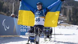 epa12801028 A handout photo made available by OIS/IOC shows Taras Rad of Ukraine celebrates with the national flag of Ukraine after winning gold in the Para Biathlon Men's Sprint Sitting at the Tesero Cross-Country Skiing Stadium during the Milano Cortina 2026 Paralympic Winter Games, Tesero, Italy,07 March 2026.  EPA/Remi Vallat for OIS/IOC HANDOUT  EDITORIAL USE ONLY/NO SALES