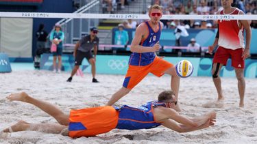 Netherlands' #02 Yorick De Groot dives to dig the ball besides his partner Netherlands' #01 Stefan Boermans as France's #01 Youssef Krou watches in the men's pool F beach volleyball match between France and Netherlands during the Paris 2024 Olympic Games at the Eiffel Tower Stadium in Paris on August 2, 2024. 
Thomas SAMSON / AFP