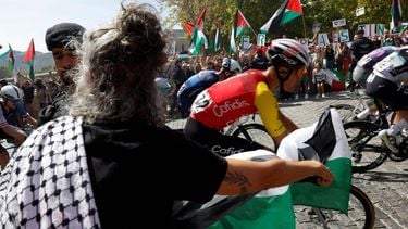 The pack rides as Pro-Palestinians protesters hold Palestinian flags during the 20th stage of the Vuelta a Espana 2025, a 156 km race between Robledo de Chavela and Bola del Mundo, in El Escorial, on September 13, 2025.   
Pierre-Philippe MARCOU / AFP