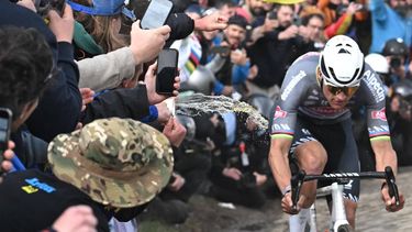 A spectator spills liquid as Alpecin-Deceuninck's Dutch rider Mathieu van der Poel cycles during the 122nd edition of the Paris-Roubaix one-day classic cycling race, 259,2 km between Compiegne and Roubaix, northern France on April 13, 2025. 
Bernard PAPON / POOL / AFP