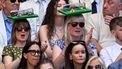 Two spectators sporting hats in the shape of a tennis court, clap during the men's singles final tennis match on the fourteenth day of the 2026 Wimbledon Championships at The All England Lawn Tennis and Croquet Club in Wimbledon, southwest London, on July 12, 2026. 
Kirill KUDRYAVTSEV / AFP