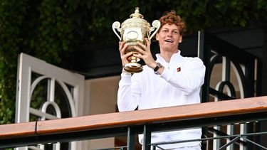 Italy's Jannik Sinner celebrates with the winner's trophy as he shows it to the crowd from the Centre Court balcony following his victory against Spain's Carlos Alcaraz at the end of their men's singles final tennis match on the fourteenth day of the 2025 Wimbledon Championships at The All England Lawn Tennis and Croquet Club in Wimbledon, southwest London, on July 13, 2025. 
Kirill KUDRYAVTSEV / AFP