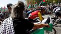 The pack rides as Pro-Palestinians protesters hold Palestinian flags during the 20th stage of the Vuelta a Espana 2025, a 156 km race between Robledo de Chavela and Bola del Mundo, in El Escorial, on September 13, 2025.   
Pierre-Philippe MARCOU / AFP
