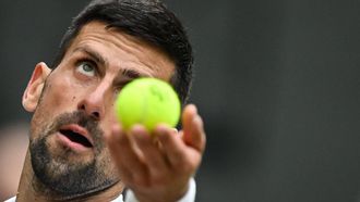 Serbia's Novak Djokovic throws the ball to serve against Italy's Lorenzo Musetti during their men's singles semi-final tennis match on the twelfth day of the 2024 Wimbledon Championships at The All England Lawn Tennis and Croquet Club in Wimbledon, southwest London, on July 12, 2024. 
ANDREJ ISAKOVIC / AFP