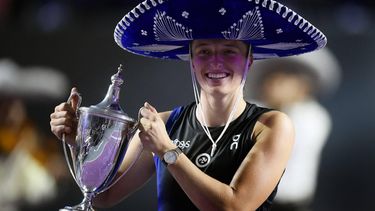 2023-11-07 00:16:38 Poland's Iga's Swiatek wearing a Mexican hat, holds her trophy on the podium during the awards ceremony after winning the WTA Finals Championship women's singles final tennis match in Cancun, Mexico on November 6, 2023. 
CLAUDIO CRUZ / AFP