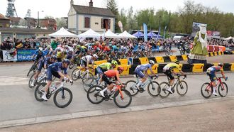 The pack of riders cycle around the new controversial chicane erected to reduce speed and mitigate crash risk at the entrance of 