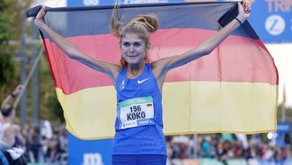 2022-10-23 10:18:10 epa10260357 Konstanze 'Koko' Klosterhalfen of Germany poses with the German national flag as she celebrates winning the Valencia Half Marathon, in Valencia, Spain, 23 October 2022.  EPA/KAI FORSTERLING