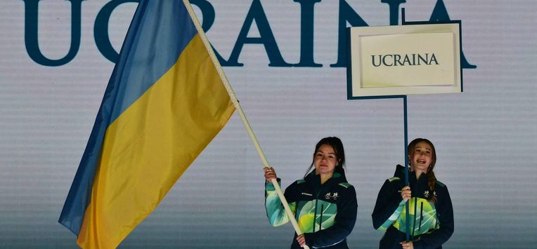 Volunteers hold a flag of Ukraine and a placard during the delegation part of the Milano Cortina 2026 Winter Paralympic Games opening ceremony at Arena di Verona in Verona on March 6, 2026. 
Stefano RELLANDINI / AFP