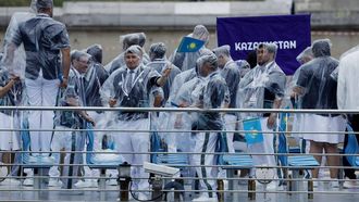 Paris 2024 Olympics - Opening Ceremony - Paris, France - July 26, 2024. Athletes in the delegation of Kazakhstan are seen wearing rain ponchos aboard a boat in the floating parade on the river Seine during the opening ceremony. 
Clodagh Kilcoyne / POOL / AFP