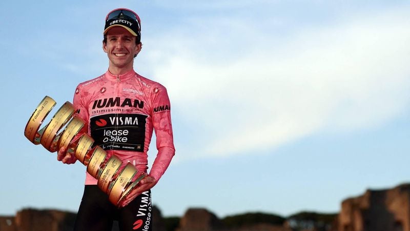 Team Visma-Lease a Bike's British rider Simon Yates wearing the pink jersey of overall leader (Maglia Rosa) celebrates holding the Trofeo Senza Fine on the podium after the 21st and last stage and winning the 108th Giro d'Italia cycling race of 143kms from Rome to Rome on June 1, 2025. 
Luca Bettini / AFP