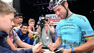 Astana Qazaqstan Team's British rider Mark Cavendish (R) signs an autograph during the 'Natourcriterium Herentals' cycling race in Herentals on July 25, 2024. 
Maarten Straetemans / Belga / AFP