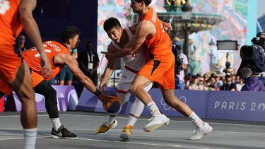 China's #09 Lu Wenbo looks to dribble past Netherlands' #44 Arvin Slagter (L) and Netherlands' #04 Jan Driessen (R) in the men's pool round 3x3 basketball game between China and the Netherlands during the Paris 2024 Olympic Games at La Concorde in Paris on July 30, 2024. 
David GRAY / AFP