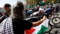 The pack rides as Pro-Palestinians protesters hold Palestinian flags during the 20th stage of the Vuelta a Espana 2025, a 156 km race between Robledo de Chavela and Bola del Mundo, in El Escorial, on September 13, 2025.   
Pierre-Philippe MARCOU / AFP
