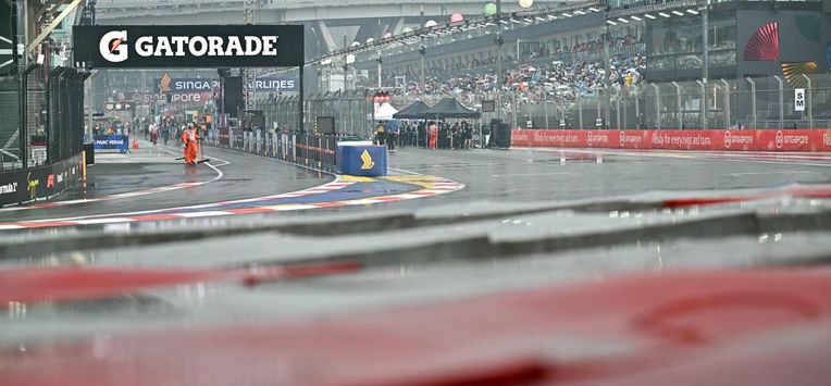 A track marshal looks on as he sweeps rain water off the track before the start of the sprint race ahead of the Formula One Singapore Grand Prix at the Marina Bay Street Circuit in Singapore on October 10, 2026. 
ANTHONY WALLACE / AFP