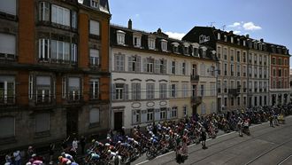 The pack of riders (peloton) cycles in the streets of Mulhouse at the start of the 14th stage of the 113th edition of the Tour de France cycling race, 155,3 km between Mulhouse and Le Markstein in the Vosges mountains, on July 18, 2026. 
Loic VENANCE / AFP