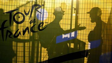 Attendees are silhouetted behind a banner bearing the Tour de France logo during the team presentation for the 111th edition of the Tour de France cycling race, in Florence in Italy, on June 27, 2024. 
Marco BERTORELLO / AFP