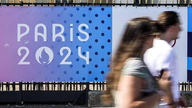 epa11483392 People walk past a sign with the Paris 2024 logo in Paris, France, 17 July 2024. From 18 to 26 July, the day of the Opening Ceremony of the Paris 2024 Olympic Games, security measures will be put in place in the French capital along the Seine river's banks and quays ahead of the main event. The Summer Olympics are scheduled to take place from 26 July to 11 August 2024 in Paris.  EPA/TERESA SUAREZ