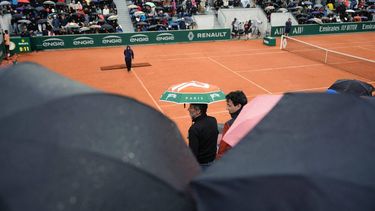 Spectators shelter under umbrellas as rain falls on a court, on day six of the French Open tennis tournament at the Roland Garros Complex in Paris on May 31, 2024. 
Dimitar DILKOFF / AFP